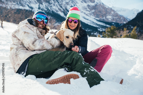 Photo couple playing with dog on the mountains, on the snowy ground