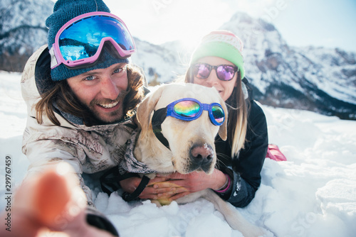 couple playing with dog on the mountains, on the snowy ground #299767459