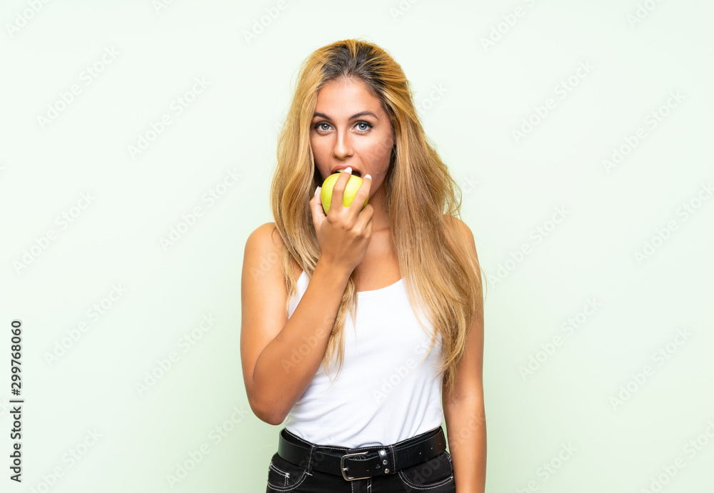 Young blonde womanYoung blonde woman with an apple over isolated background Young blonde womanYoung blonde woman with an apple over isolated background