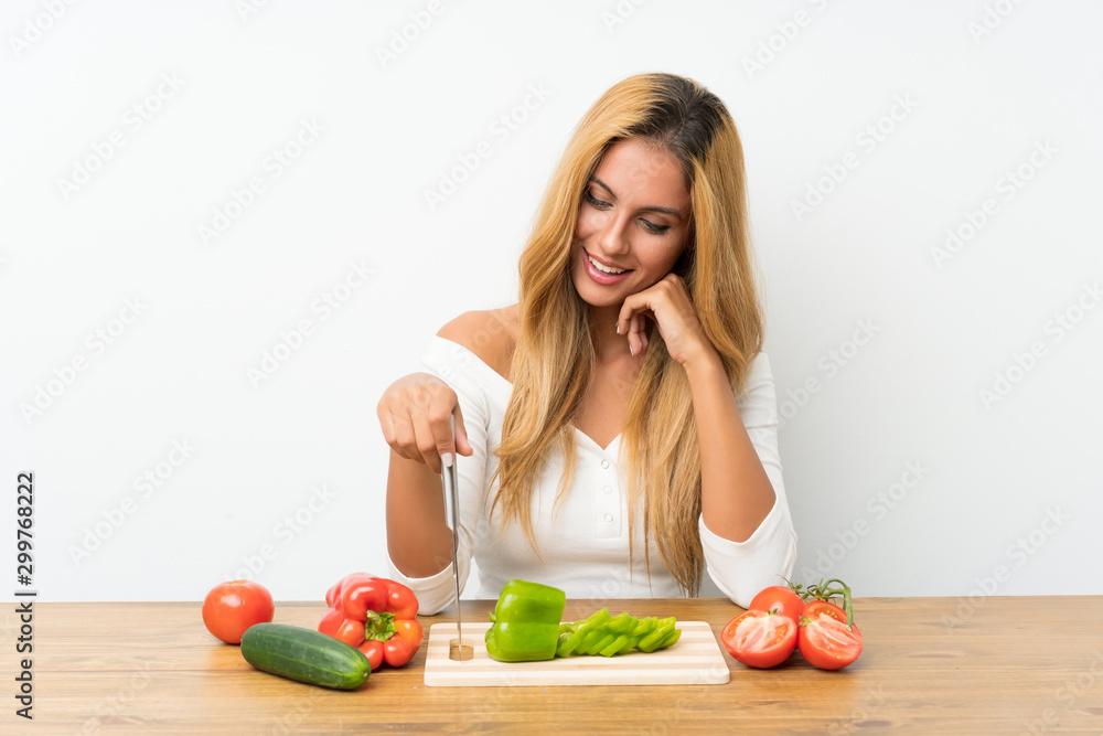 Young blonde woman with vegetables in a table Young blonde woman with vegetables in a table