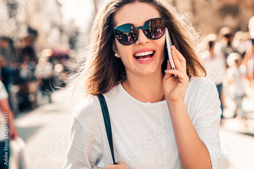Young stylish woman using phone walking on the street, wearing trendy outfit.