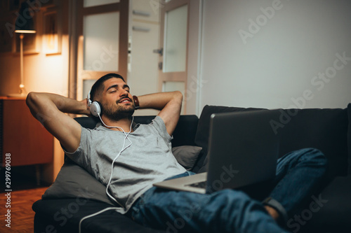 man relaxing in his apartment listening to a music photo
