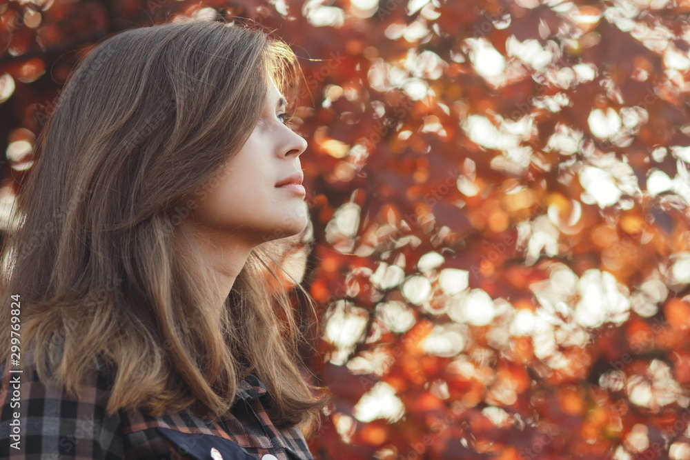 profile of a beautiful young woman looking up gratefully, girl walking through autumn nature in a park profile of a beautiful young woman looking up gratefully, girl walking through autumn nature in a park