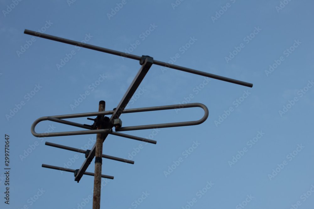 View of Television antenna on the roof top with blue sky background View of Television antenna on the roof top with blue sky background