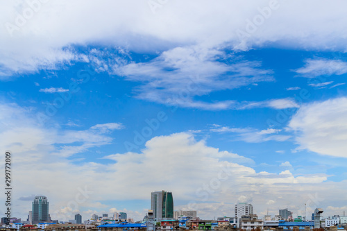 White fluffy clouds flying on the fresh blue sky after hard raining over group of building and house with copy space. Background for business target or meteorology or inspiration.