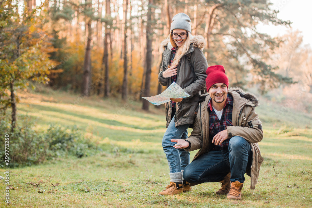 Traveler couple with map, compass and backpack exploring forest. Freedom and active travel concept. Traveler couple with map, compass and backpack exploring forest. Freedom and active travel concept.