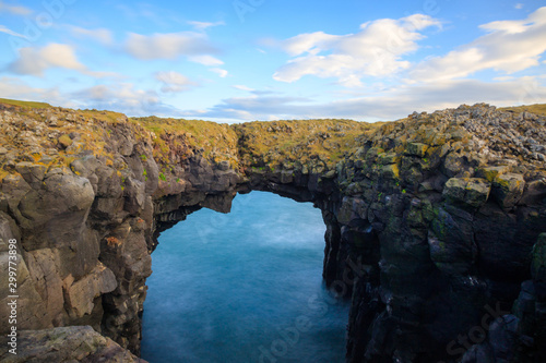 West coast sea cliffs of Snaefellsnes Peninsula on Iceland in long exposure photo. Pure blue water with high cliffs above sea. Beautiful colourful scenic view of basalt rock reef..