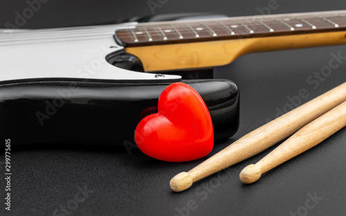 Fototapeta Red heart with guitar and drumsticks on black. Love music.