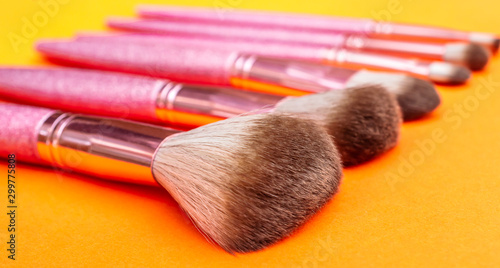 Brushes for makeup on bright orange background.