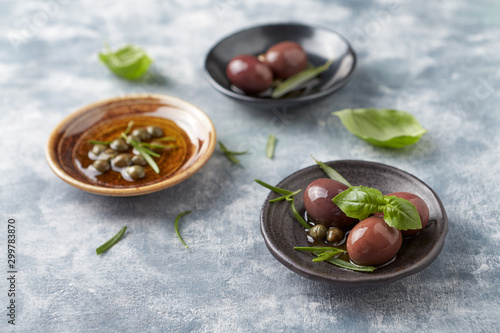 Kalamata olives and capers on bright wooden background. Close up. 