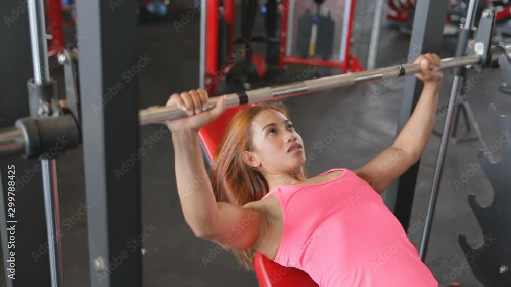 Barbell incline bench press woman in multipower smith machine workout at gym Barbell incline bench press woman in multipower smith machine workout at gym