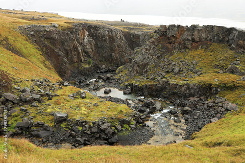 Hengifoss canyon and waterfall, the third highest waterfall in Iceland, surrounded by basaltic strata with red layers of clay between the basaltic layers