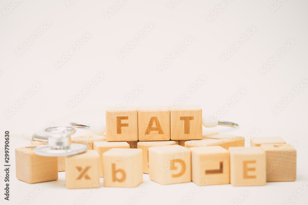 Fototapeta premium FAT word on wooden cube and stethoscope.