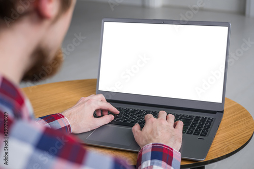 Mock up, copyspace, education, template, entertainment and technology concept. Man student typing on laptop computer keyboard with white blank screen on wooden table in home interior - mockup image