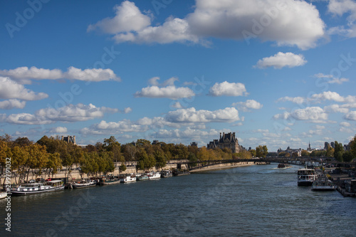  View of river channel in Paris France fluffy cloudy blue sky  © Rebecca