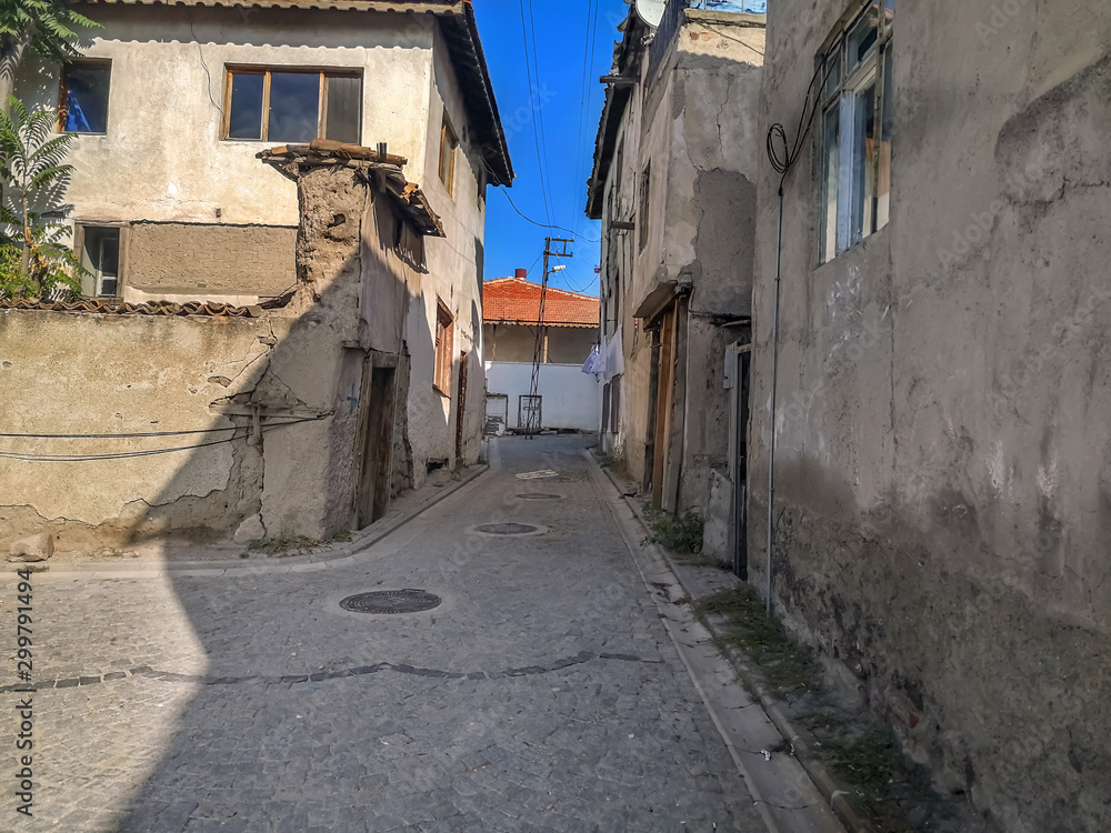 Street of old residential buildings in the slums of Ankara Castle in the capital of Turkey. Stone road, gray cracked walls of houses and red tile roof