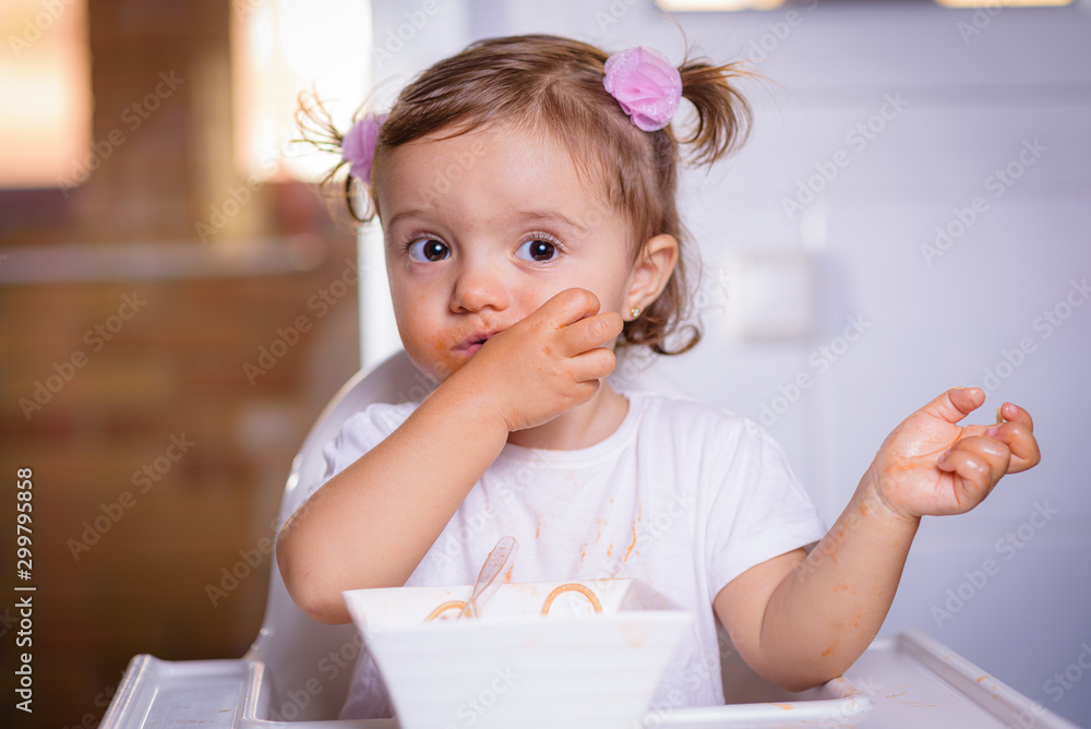 Adorable little girl eating spaghetti with Bolognese sauce with her hands. Infant feeding Adorable little girl eating spaghetti with Bolognese sauce with her hands. Infant feeding