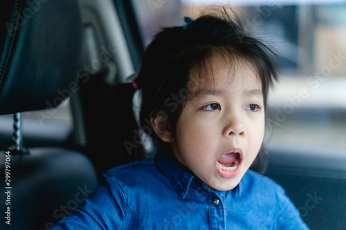 Transport, safety, childhood road trip and people concept - happy little girl sitting in car, Child in auto car and laughing and smile.Happy Little asian girl child showing front teeth with big smile.