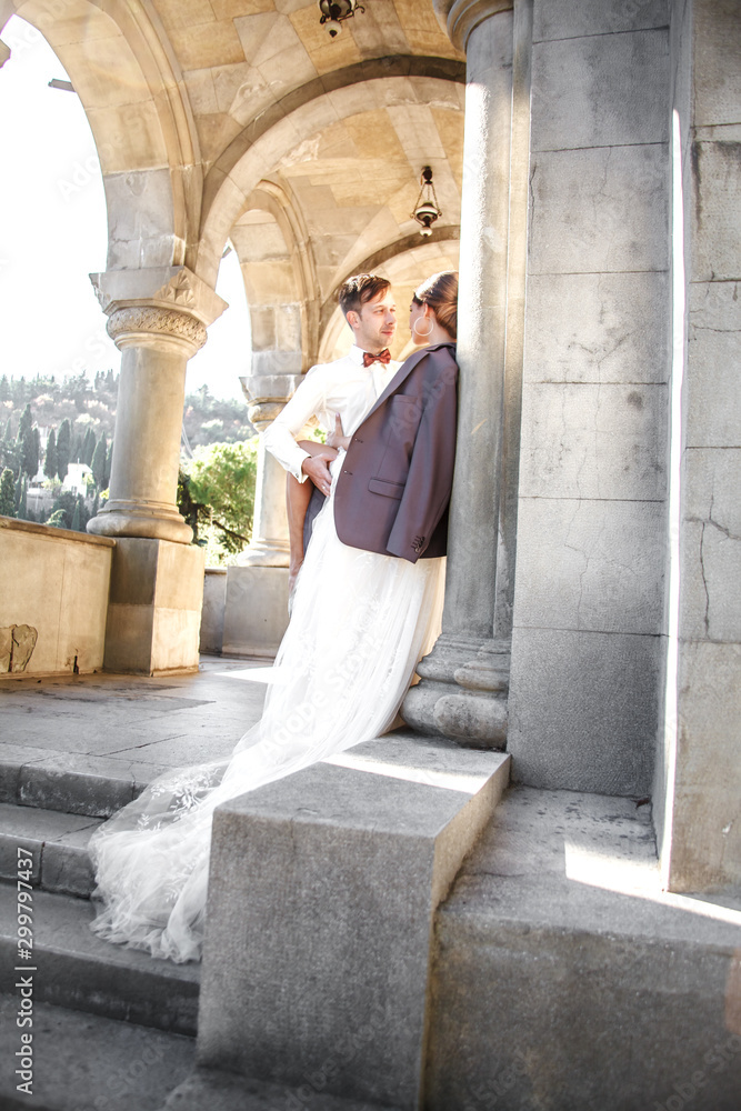 Happy people in wedding relationship are kissing in the old street of the city. Bride and groom wearing the marriage clothes, white elegant dress and suit. Happy people in wedding relationship are kissing in the old street of the city. Bride and groom wearing the marriage clothes, white elegant dress and suit.