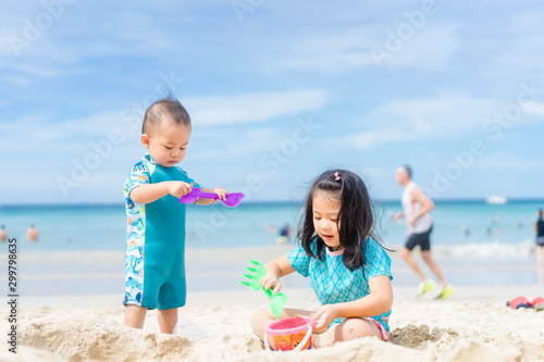 Photography 4 years old Little asian girl playing on the beach with her 1 year old baby brother
