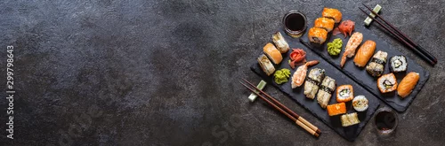 Obraz  z motywem sushi rolls with rice and fish, soy sauce on a dark stone background