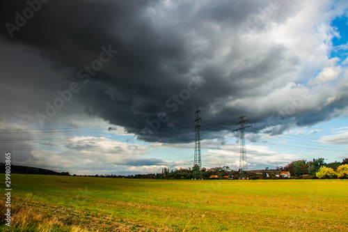 landscape with field, blue sky and dark rain clouds