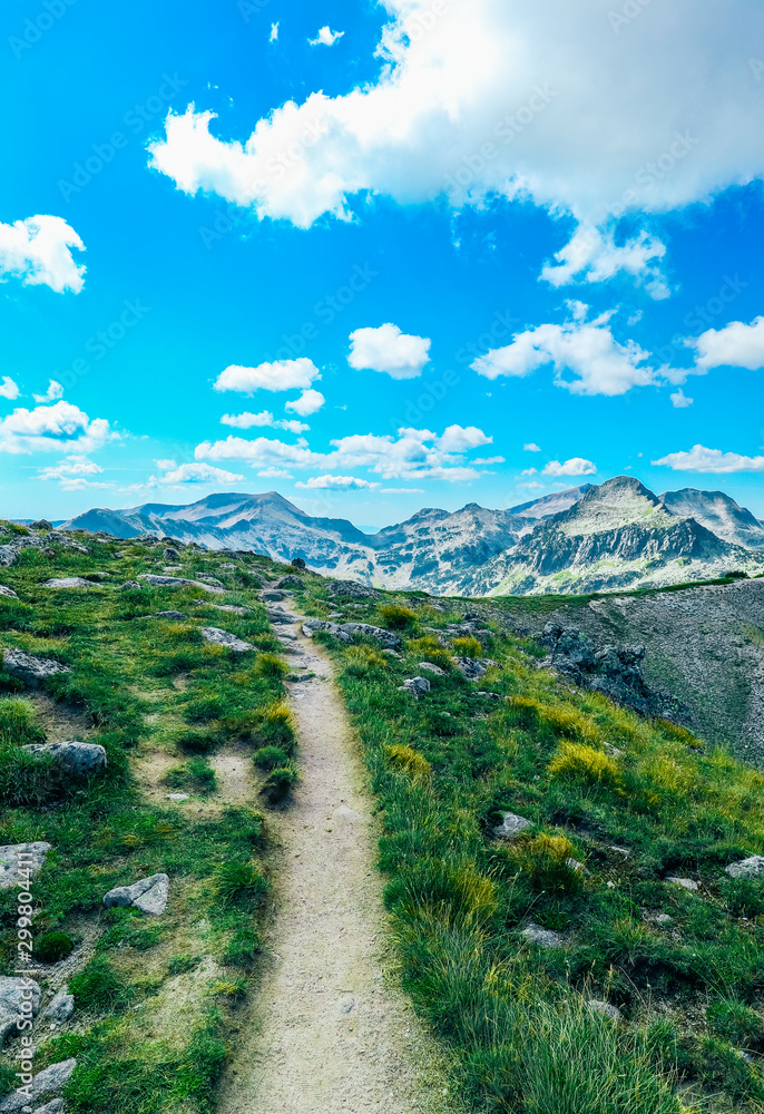 Amazing alpine mountain landscape, sunny hiking trail, grass and rocks, easy walk, but long way to go. Amazing alpine mountain landscape, sunny hiking trail, grass and rocks, easy walk, but long way to go.