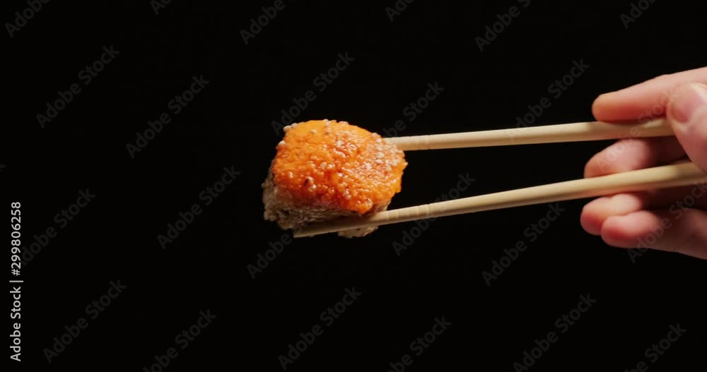Appetizing Sushi in chopsticks on black background Appetizing Sushi in chopsticks on black background