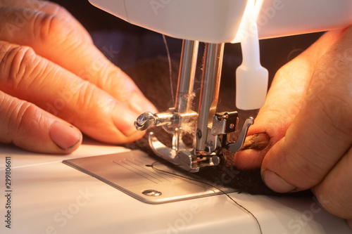 Fototapeta Naklejka Na Ścianę i Meble -  Man repairing a clothe with a sewing machine
