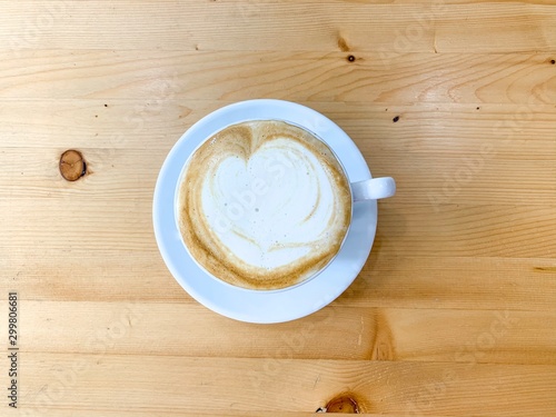 White cup of hot coffee with latte art on wooden table