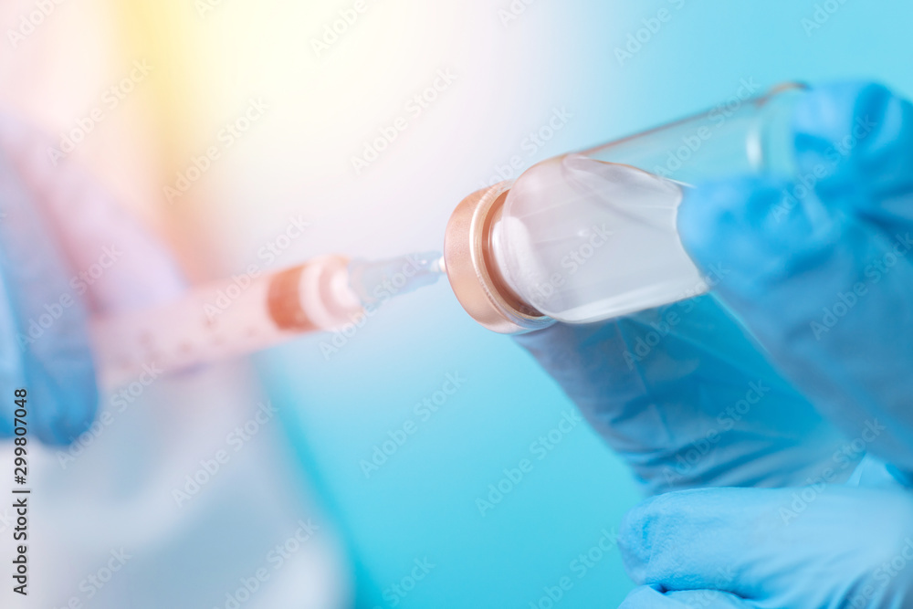 Doctor hand holding syringe and vaccine in blue gloves white coat, sun light. Concept disease injection Doctor hand holding syringe and vaccine in blue gloves white coat, sun light. Concept disease injection