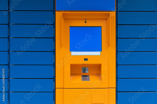 Orange cashpoint minibank with blank copyspace screen on blue panel tile background