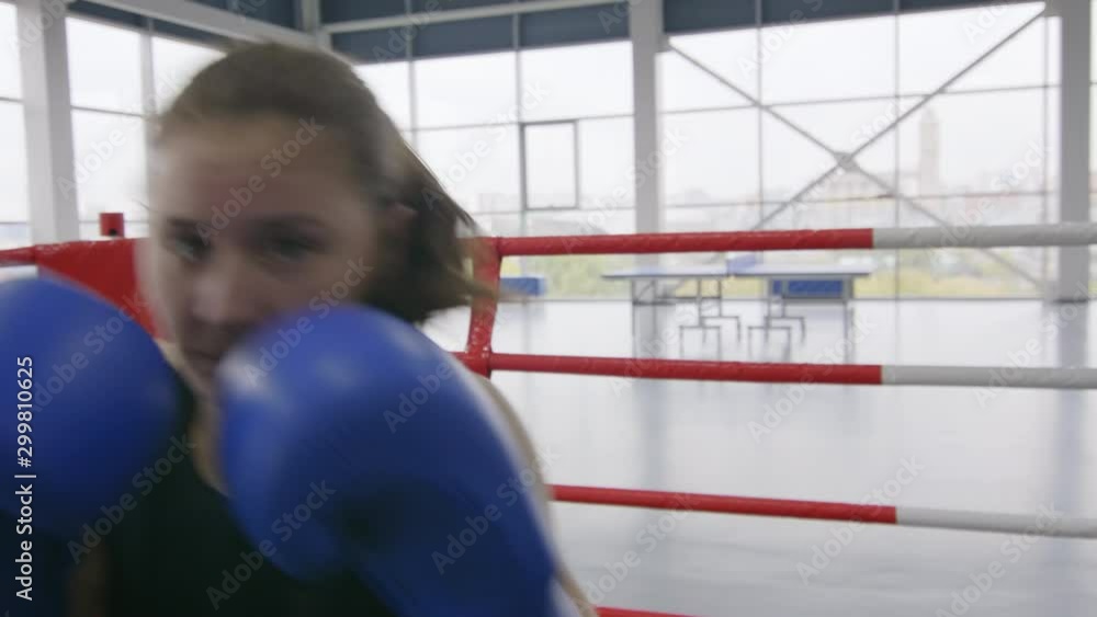 Close up shot of professional female boxer of Caucasian ethnicity in gloves punching at camera while training on ring in gym Close up shot of professional female boxer of Caucasian ethnicity in gloves punching at camera while training on ring in gym
