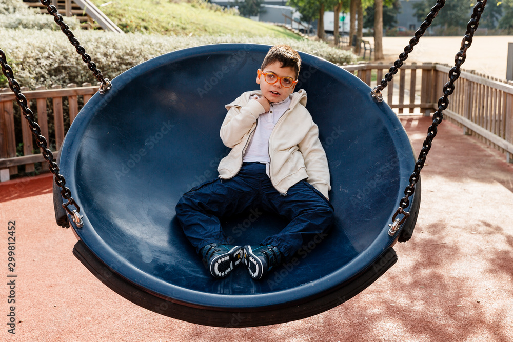 niño en el parque en columpio grande redondo balanceándose y riendo . Niño  con pluri discapacidad. Stock Photo | Adobe Stock