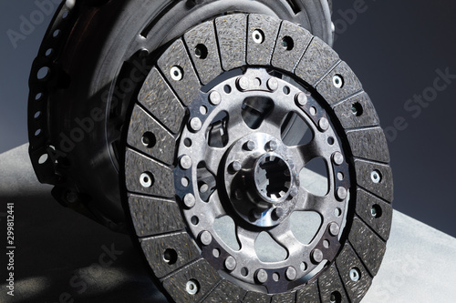 Close-up picture of a part of car, black clutch disk isolated on black background with light photo