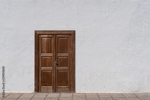 rustic brown wooden entrance door in weathered white wall