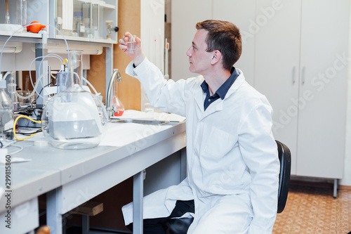 male scientist conducts chemical experiments with fluids in medical laboratory photo