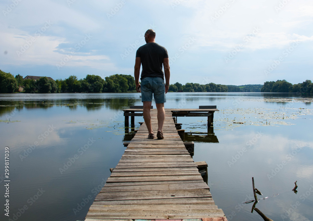 Back view of boy with casual clothing on wooden pier. summer day. Concept freedom