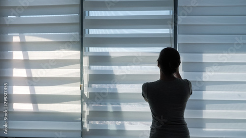 Woman is opening blinds in the morning in her modern apartment, copy space