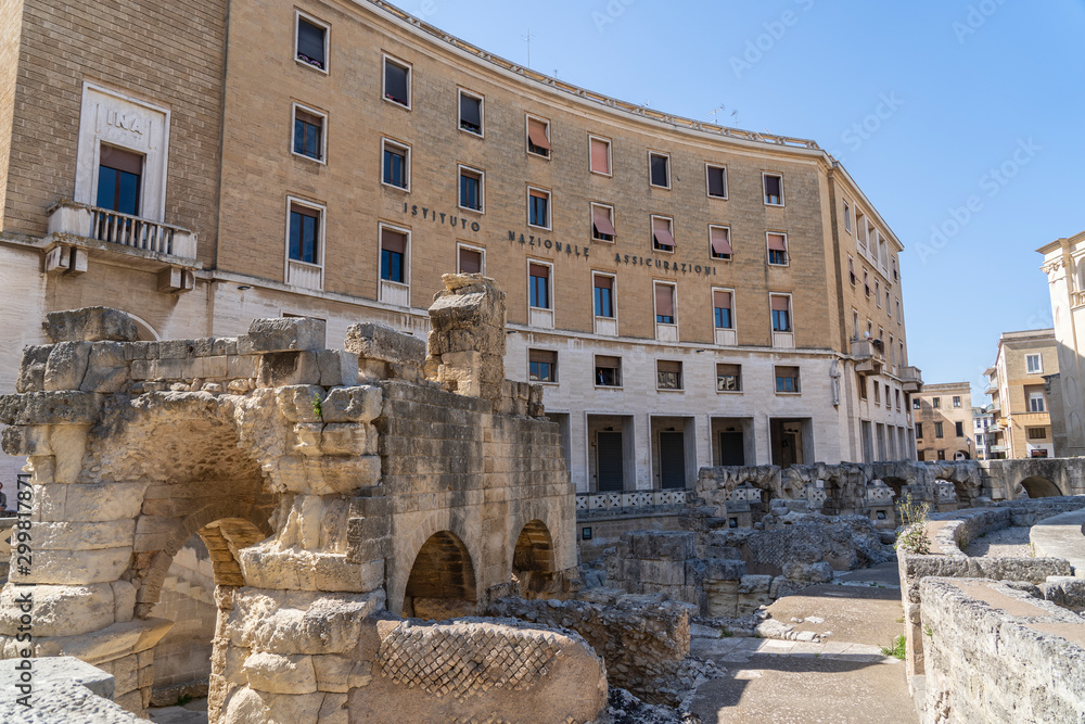 Roman Amphitheatre in Lecce, Puglia (Apulia), southern Italy. Ruins of a Roman amphitheater. INA (Istituto Nazionale Assicurazioni) Building behind.