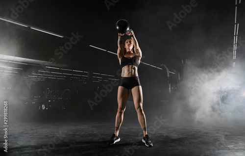 Athletic girl does exercises using sports equipment in a gym.