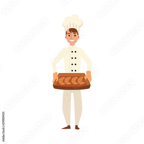 A young Caucasian male baker and chef in a white uniform and cook hat.