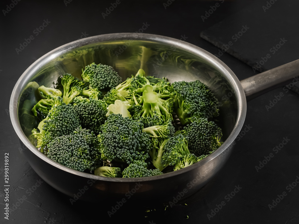Cauliflower sliced into pieces is in a steel pan. Black background. Cooking concept. Close-up. Cauliflower sliced into pieces is in a steel pan. Black background. Cooking concept. Close-up.