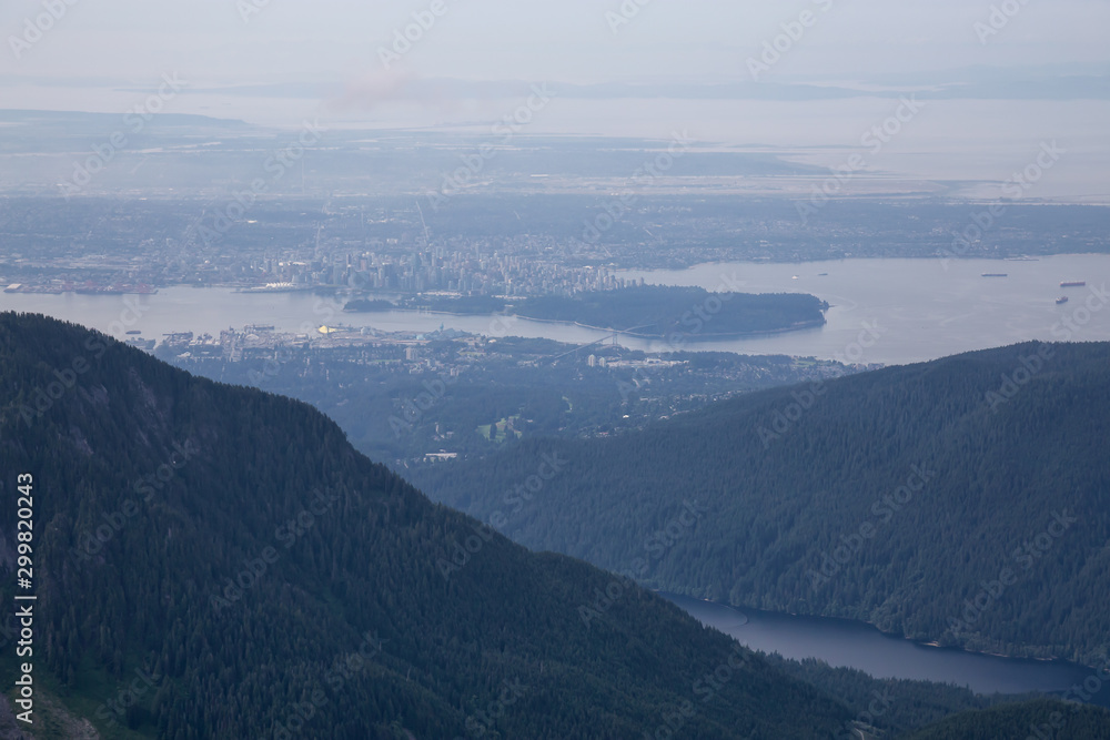 Aerial View of Grouse Mountain with Downtown City in the background during a sunny and hazy summer day. Taken in North Vancouver, BC, Canada.
