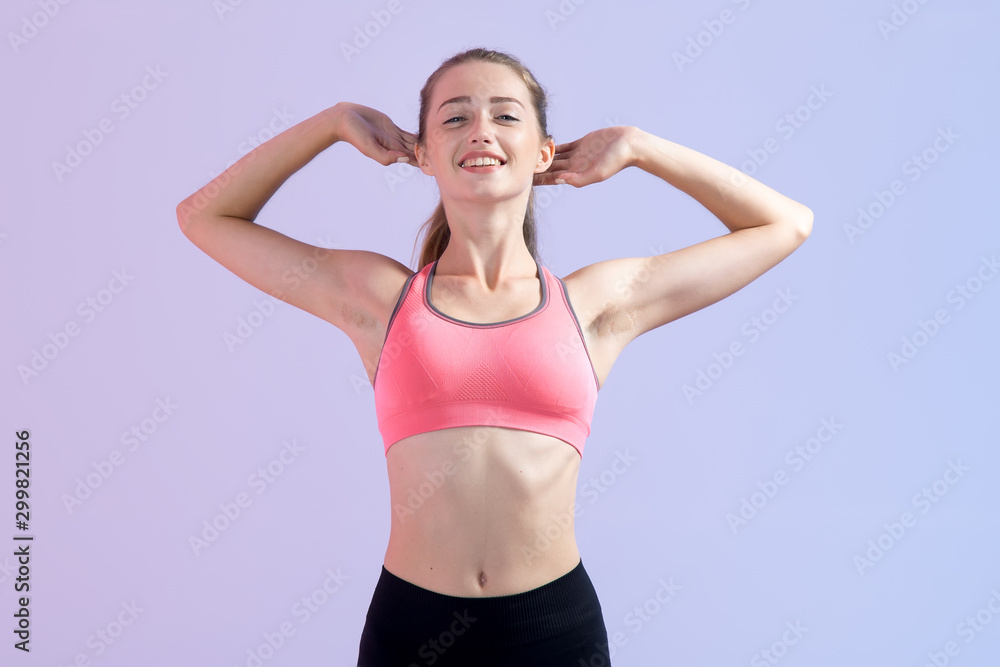 Young fitness woman. Female doing exercises stretching raising his hands behind his head, standing on a pink purple background. Young fitness woman. Female doing exercises stretching raising his hands behind his head, standing on a pink purple background.