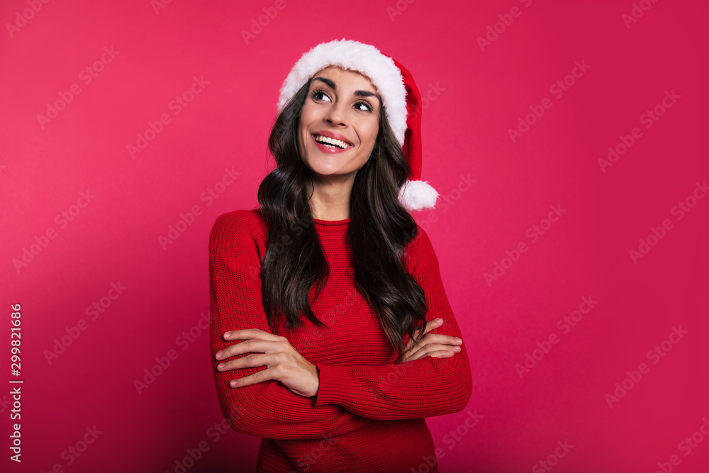I wish… Beautiful girl in a ruby red knitted sweater and Santa Claus hat is posing with her arms folded, looking at the left upper corner with an irresistible smile. I wish… Beautiful girl in a ruby red knitted sweater and Santa Claus hat is posing with her arms folded, looking at the left upper corner with an irresistible smile.