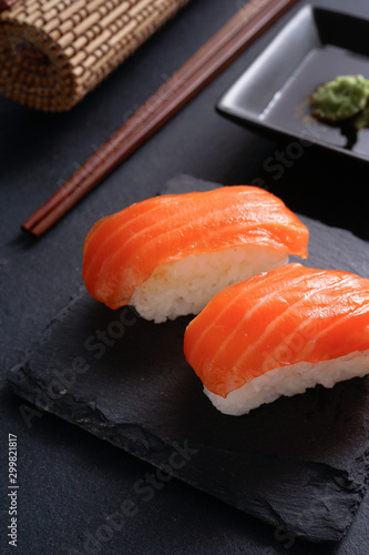 Salmon Nigiri Sushi on black slate stone with soy sauce and wasabi 