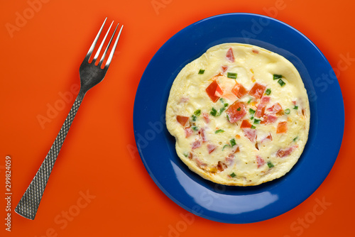 omelet on a blue plate on an orange background. healthy breakfast top view.