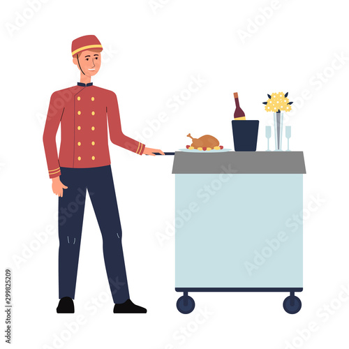 Hotel food service employee in red uniform pushing cart with luxury meal.