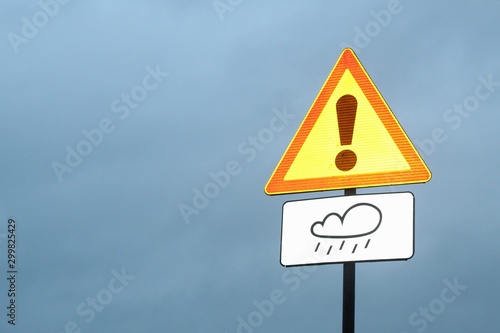 Warning road sign "danger"and" wet road".The sign glows in the headlights of passing cars.Road safety.Heavy rain and bad weather.